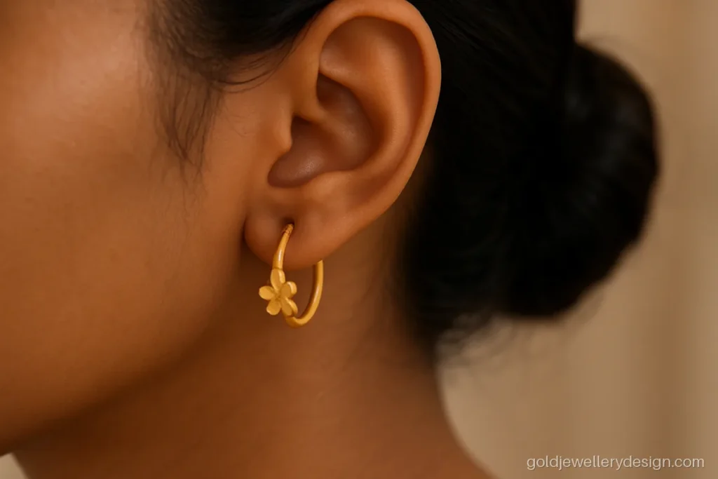 Young woman's ear with a small gold bali that has a flower on the front