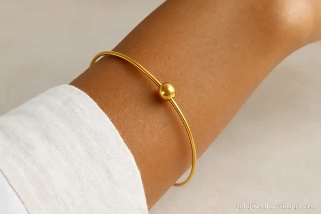 Thin wire gold bangle with a single round ball charm, very light