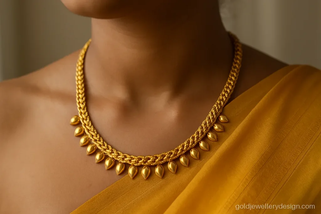 Long necklace gold design with a thick rope chain and small mango drops worn with a saree