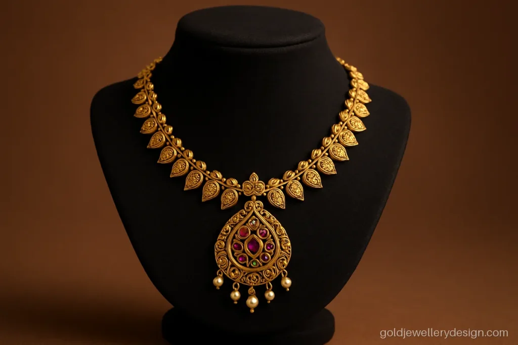 Antique gold necklace with red and green kemp-look stones on a jewellery bust