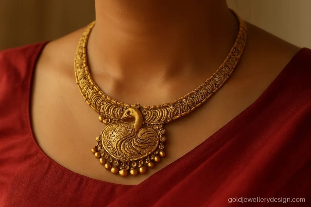 Wedding gold necklace design with a peacock pendant worn with a red silk saree