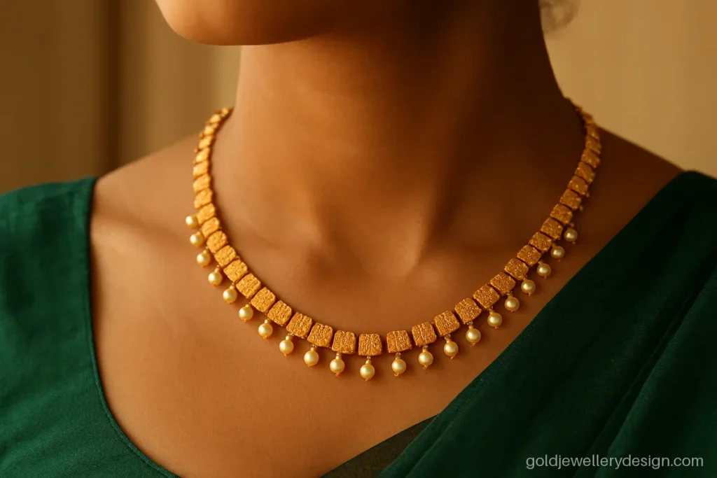 Gold necklace design for women with a fringe of pearl drops worn with a silk saree