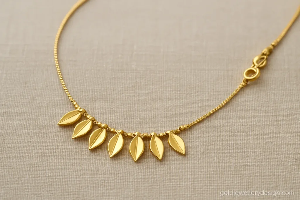 Simple gold necklace design with a row of small leaves on a fine box chain