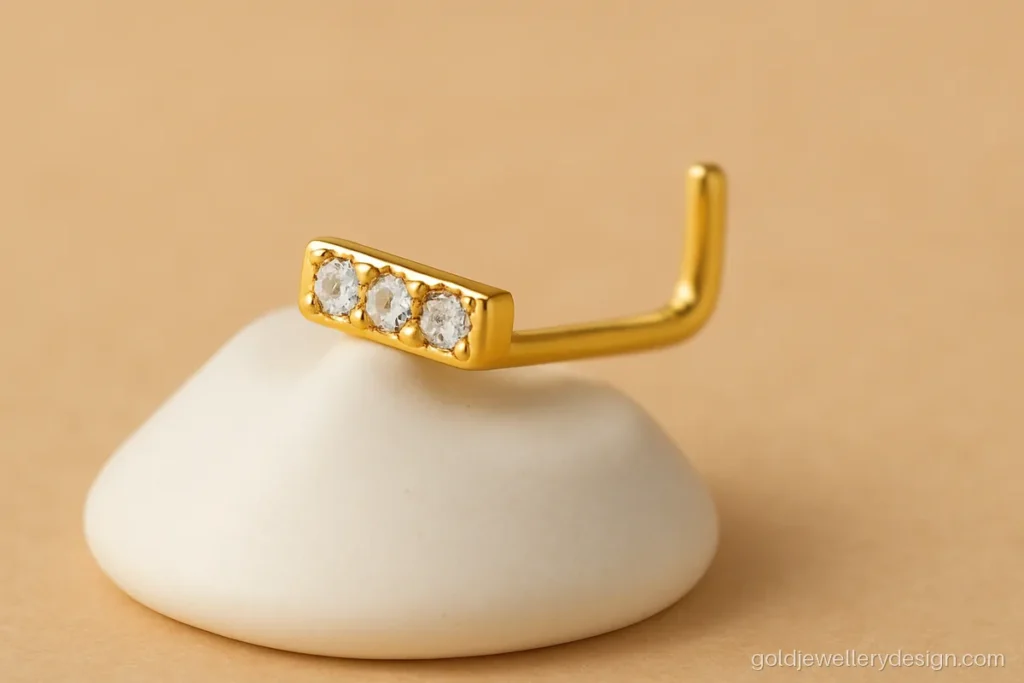 Gold nose pin with a short bar top, three tiny CZ stones and an L-shaped pin