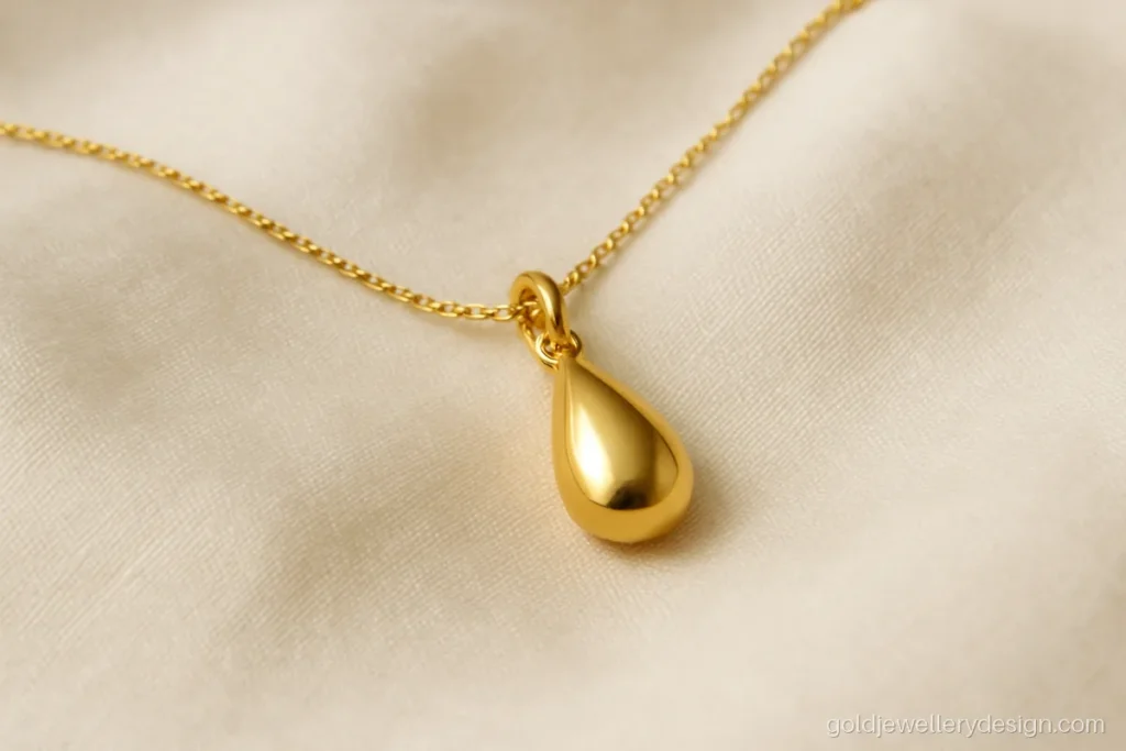 Simple gold pendant design shaped like a small polished teardrop on a fine chain