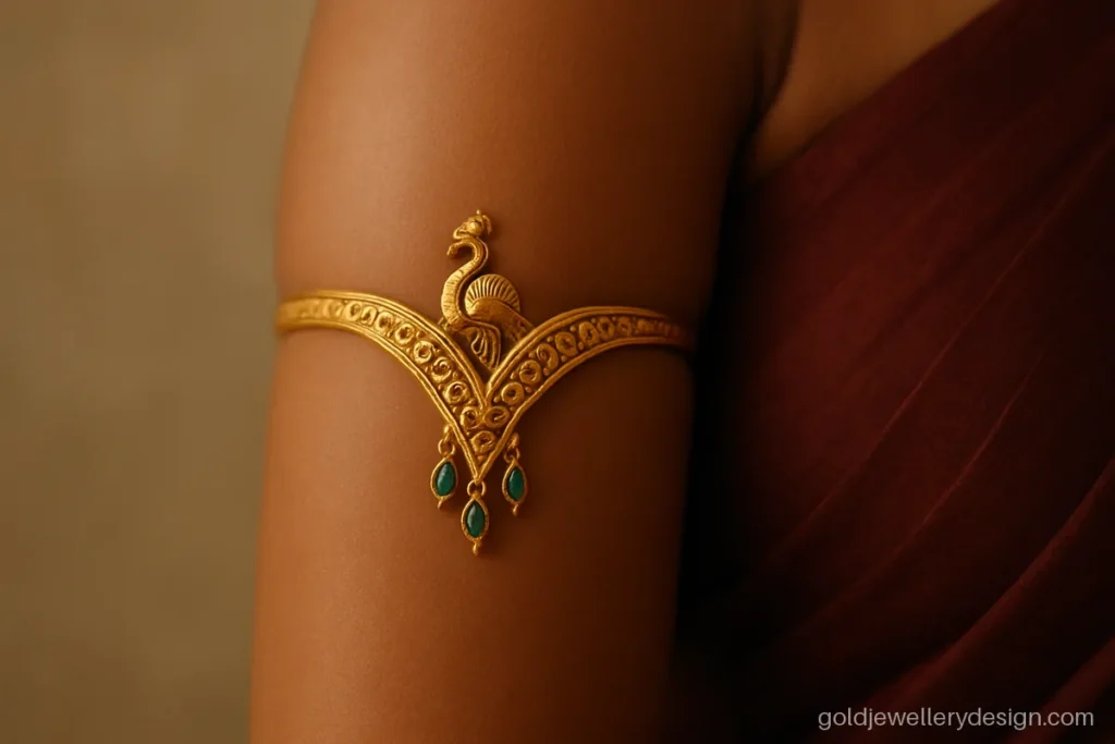 Gold vanki armlet with a peacock centre and emerald drops worn on the upper arm