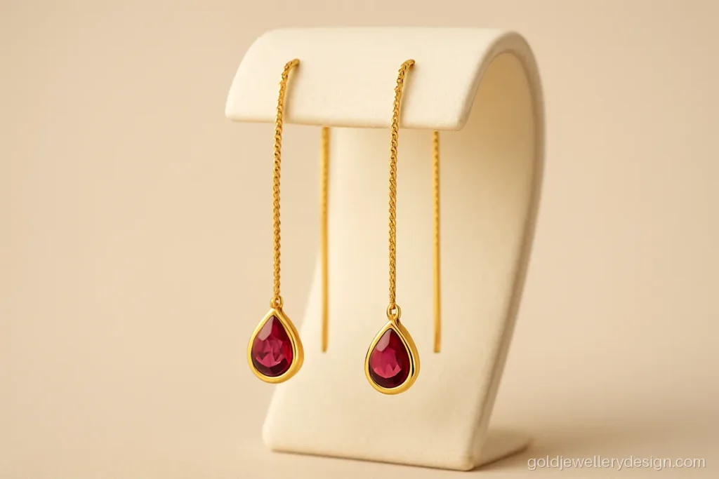 Gold earrings design sui dhaga style with a ruby teardrop at the end