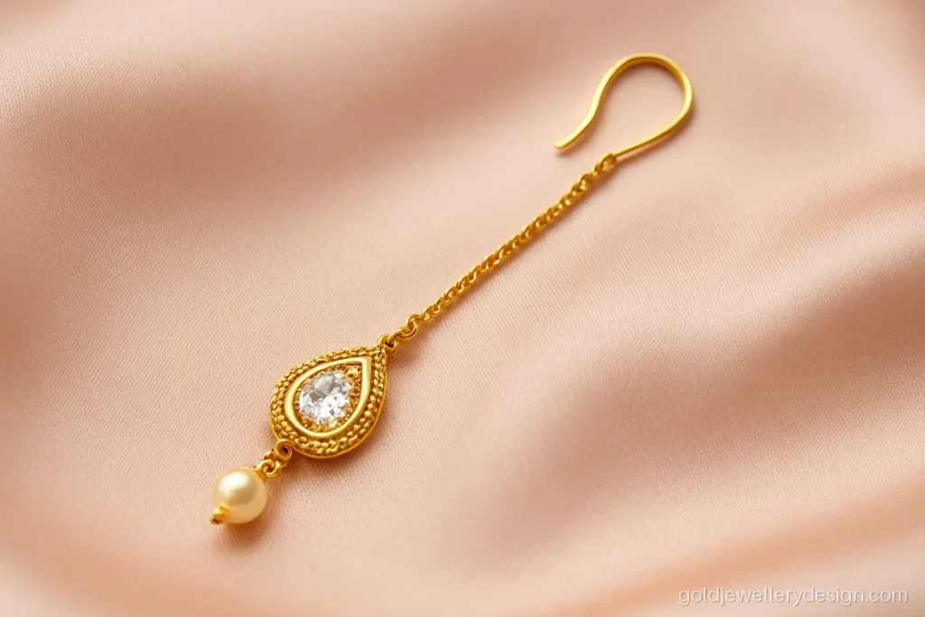 Small gold tika design with teardrop pendant and a single white stone